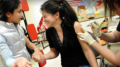 Emma Thomas, 10, left, comforts her cousin, Macey Thomas, 13, as Macey got an H1N1 vaccine at Moon Middle School yesterday. Some 600 doses of vaccine were given to students from Moon Area School District.