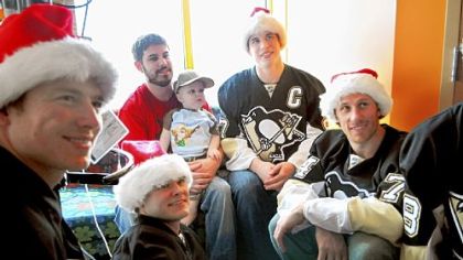 Blake Thomas and his son Michael, 2, pose for a photo with Penguins players, from left, Ruslan Fedotenko, Chris Kunitz, Sidney Crosby, and Jay McKee on Dec. 8. The Penguins players made their 26th annual team visit to patients at Children's Hospital and delivered gifts, posed for photos, and signed autographs.