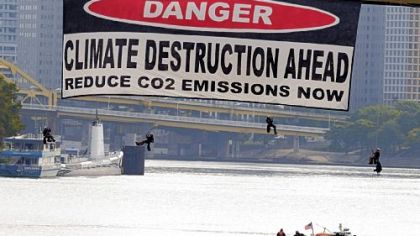 Four protesters dangle from the West End Bridge, about 50 feet above the Ohio River, after hanging a huge banner from the span. Four others lashed themselves to the bridge railing and hung just outside it.