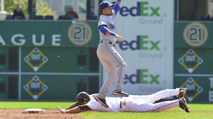 Dodgers shortstop Juan Castro jumps to catch the ball as the Pirates first baseman/outfielder Garrett Jones slides safely into second base.