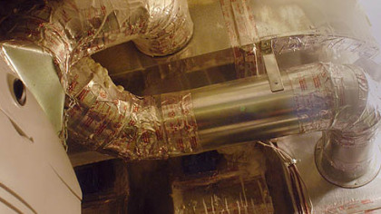 The heating system uses metal ductwork sealed with tape. Sprayed insulation can be seen at the top.