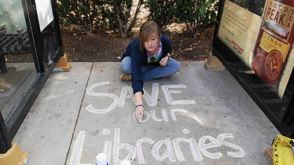 Katie Bouvy, a University of Pittsburgh student from Carrick, shows her support of the libraries by writing on the sidewalk at Forbes Avenue and Craig Street in Oakland yesterday.