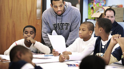 Pitt basketball player Chase Adams works with students at University Prep in the Hill District on an exercise to write a defining statement about themselves. Adams, coach Jamie Dixon and other players are involved with the community program working with children at the school.