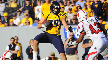West Virginia's Tyler Urban looks to carry the ball past Louisville's Chris Campa, right, during the fourth quarter of yesterday's game in Morgantown.