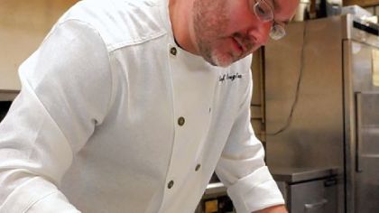 Chef Douglass Dick drizzles a balsamic reduction on the salad of mixed local organic heirloom tomatoes with goat's milk Feta cheese he's preparing in the kitchen of his Bona Terra restaurant in Sharpsburg.