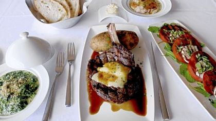 A bone-in ribeye with dark beer sauce and a gorgonzola crust accompanied by creamed spinach, potatoes au gratin and a tomato basil salad at Bistecca Steakhouse at the Meadows Racetrack & Casino.