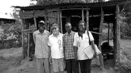 George McGee, second from left, with Stephen Omondi Okongo, Stephen's brother Dennis and a CFCA social worker outside Stephen's old mud house ...