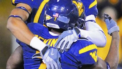 West Virginia's Alric Arnett, top, celebrates with Noel Devine.