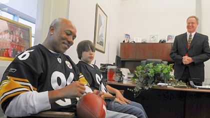 Pittsburgh Steelers receiver Hines Ward signs autographs with eighth-grader David Grove and Principal Robert Gallagher at Freedom Area Middle School. David got to spend time with Ward as winner of an NFL contest to encourage exercise.